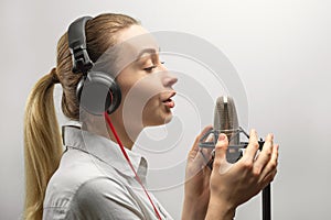 Music, show business, people and voice concept - singer with headphones and microphone singing a song in recording studio,