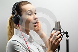 Music, show business, people and voice concept - singer with headphones and microphone singing a song in recording studio,