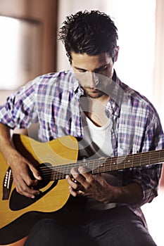 Music soothes the soul. A handsome young musician playing a guitar.