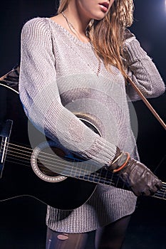 Music Styles Concepts and Ideas. Young Caucasian Female Music Player Posing with Guitar Against Black.