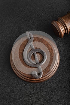 Music symbol treble clef and judge gavel on black background. Music piracy and copyright infringement. Vertical frame