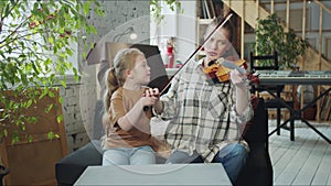 The music teacher takes the violin from the student and shows how to play