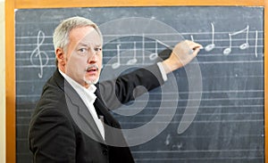 Music teacher writing notes on a blackboard