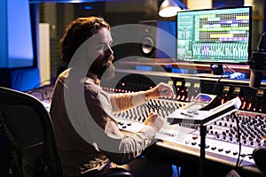 Music technician mixing and mastering songs with motorized faders and knobs