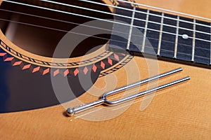 Music tuning fork on acoustic guitar strings