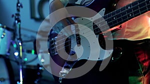 Music video punk, heavy metal or rock group. Closeup view of male hands playing bass guitar live during the show in blue