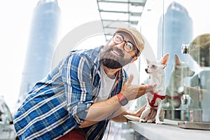 Modern man listening to music using earphones and walking with dog