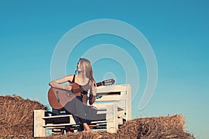 Music woman play guitar on wooden bench on blue sky. Music, woman guitarist perform concert on acoustic guitar.