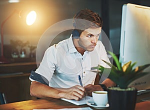 Music and work go together well. Cropped shot of a young designer working late at the office while listening to music