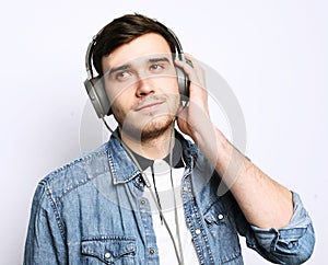 Music! Young man wearing headphones and holding mobile phone.