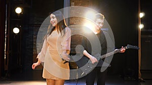 Musical artists sing and play electric guitar on stage. Contemporary duet band