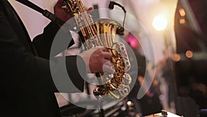 Musical band group playing song, performing on concert musician stage with lights. Saxophone player playing a solo in