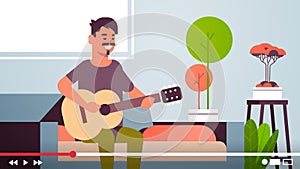 Musical blogger recording online video stream for vlog male vlogger playing guitar blogging concept modern living room