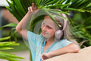 Musical cheerful mood. A little girl listens to music on headphones. Child girl in big headphones enjoys the music