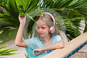 Musical cheerful mood. A little girl listens to music on headphones. Child girl in big headphones enjoys the music