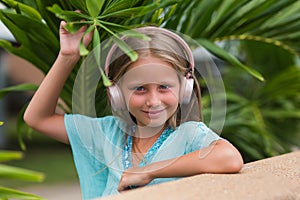 Musical cheerful mood. A little girl listens to music on headphones. Child girl in big headphones enjoys the music