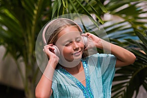 Musical cheerful mood. A little girl listens to music on headphones. Child girl in big headphones enjoys the music