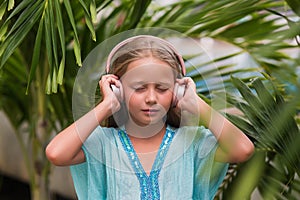 Musical cheerful mood. A little girl listens to music on headphones. Child girl in big headphones enjoys the music