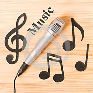 Musical concept. microphone and music notes on wooden background