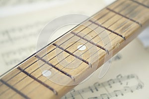 conceptual composition of a wooden guitar on the background sheet music old yellowed and clean paper