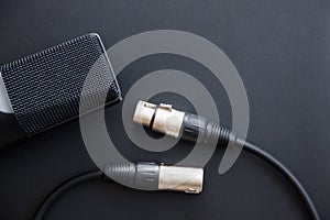 Musical equipment, Professional condenser studio microphone with xlr cable, dark color. Close up from above