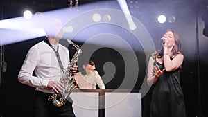 Musical group band of singer vocalist woman, saxophonist sax, dj man playing song performing on concert musician stage