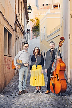 A musical group of three people on an old European street. The band consists of two men and one girl. Men with a double bass and a