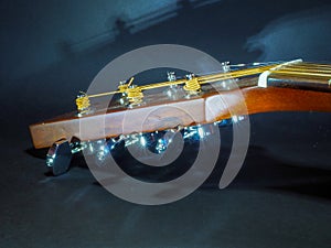 Musical instrument classical acoustic guitar of light color with steel pins and silver strings on a dark background