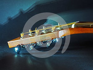 Musical instrument classical acoustic guitar of light color with steel pins and silver strings on a dark background