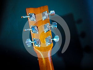 Musical instrument classical acoustic guitar of light color with steel pins and silver strings on a dark background