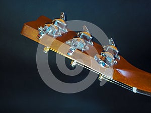 Musical instrument classical acoustic guitar of light color with steel pins and silver strings on a dark background