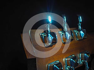 Musical instrument classical acoustic guitar of light color with steel pins and silver strings on a dark background