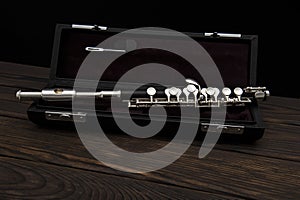 Musical instrument, flute with a case on a wooden surface on a black background