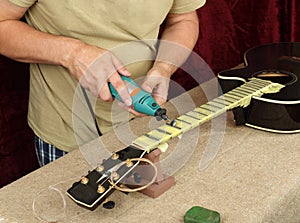 Guitar repair and service - Worker polishing acoustic guitar neck frets dremel and paste GOI photo