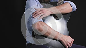 musical instrument, young man sits with a guitar in his hands on a dark background