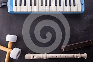 Musical instruments background with flute, pianika, harmonica, and bass stick on black wooden.