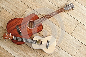 Musical instruments background. Top view of the acoustic and ukulele guitars lying close to each other against the photo