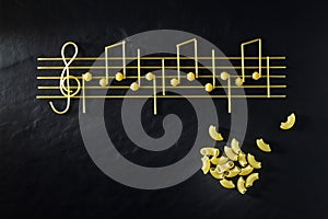 Musical Italian pasta in the form of notes, isolated on a black textural background