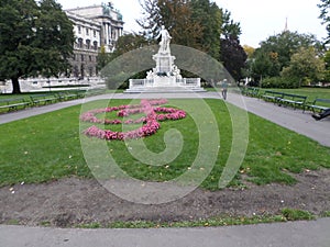 Musical note made from flowers at Burggarten at the Ringstrasse and sculpture of Mozart afar.