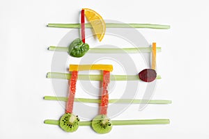 Musical notes made of fruits and vegetables on white background