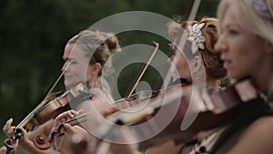 Musical quartet. Three violinists and cellist playing music. Close up.