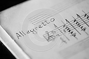 Musical tempo Allegretto in a music book with hand-written notes photo