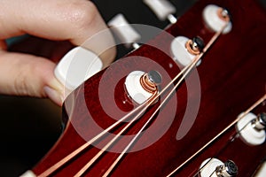 The musician adjusts the acoustic guitar with his hand