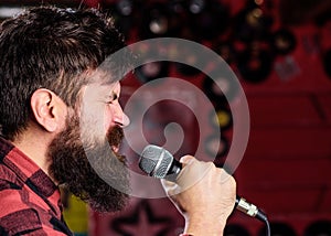 Musician with beard and mustache singing song in karaoke. Punk rock concept. Man with tense face holds microphone