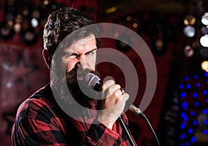 Musician with beard and mustache singing song in karaoke. Rock star concept. Man with enthusiastic face holds microphone
