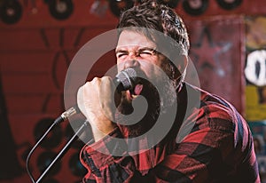 Musician with beard and mustache singing song in karaoke. Rock star concept. Man with tense face holds microphone