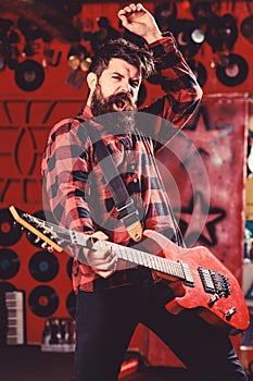 Musician with beard play electric guitar. Man with enthusiastic face