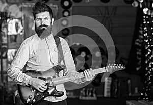 Musician with beard play electric guitar. Rock music concept. Man with strict face play guitar, singing song, play music