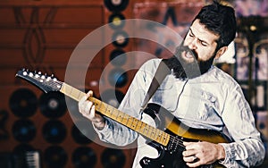 Musician with beard play electric guitar. Rock music concept. Talented musician, soloist, singer play guitar in music