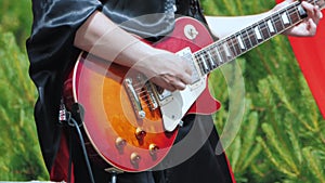 A musician in black gothic clothes plays the electric guitar.